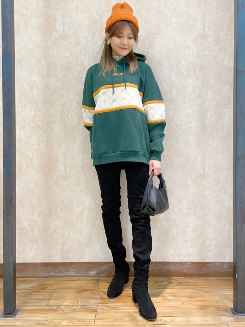 ブラウン系のブルゾン、グリーン系のパーカー、ブラック系のデニムパンツを着用したレディースの冬コーディネートの3枚目の写真