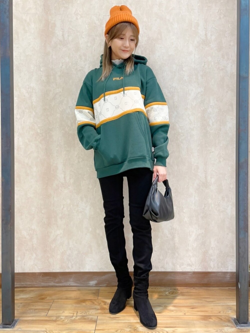 ブラウン系のブルゾン、グリーン系のパーカー、ブラック系のデニムパンツを着用したレディースの冬コーディネートの2枚目の写真