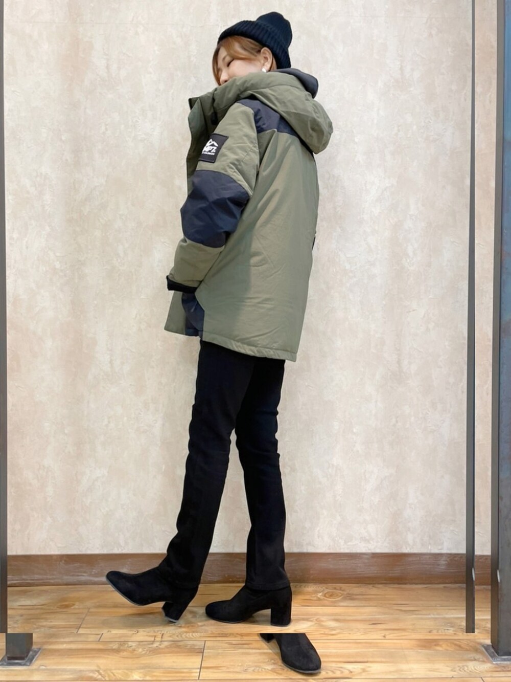 グリーン系のダウンジャケット/コート、ホワイト系のパーカー、ブラック系のハンドバッグを着用したレディースの冬コーディネートの2枚目の写真