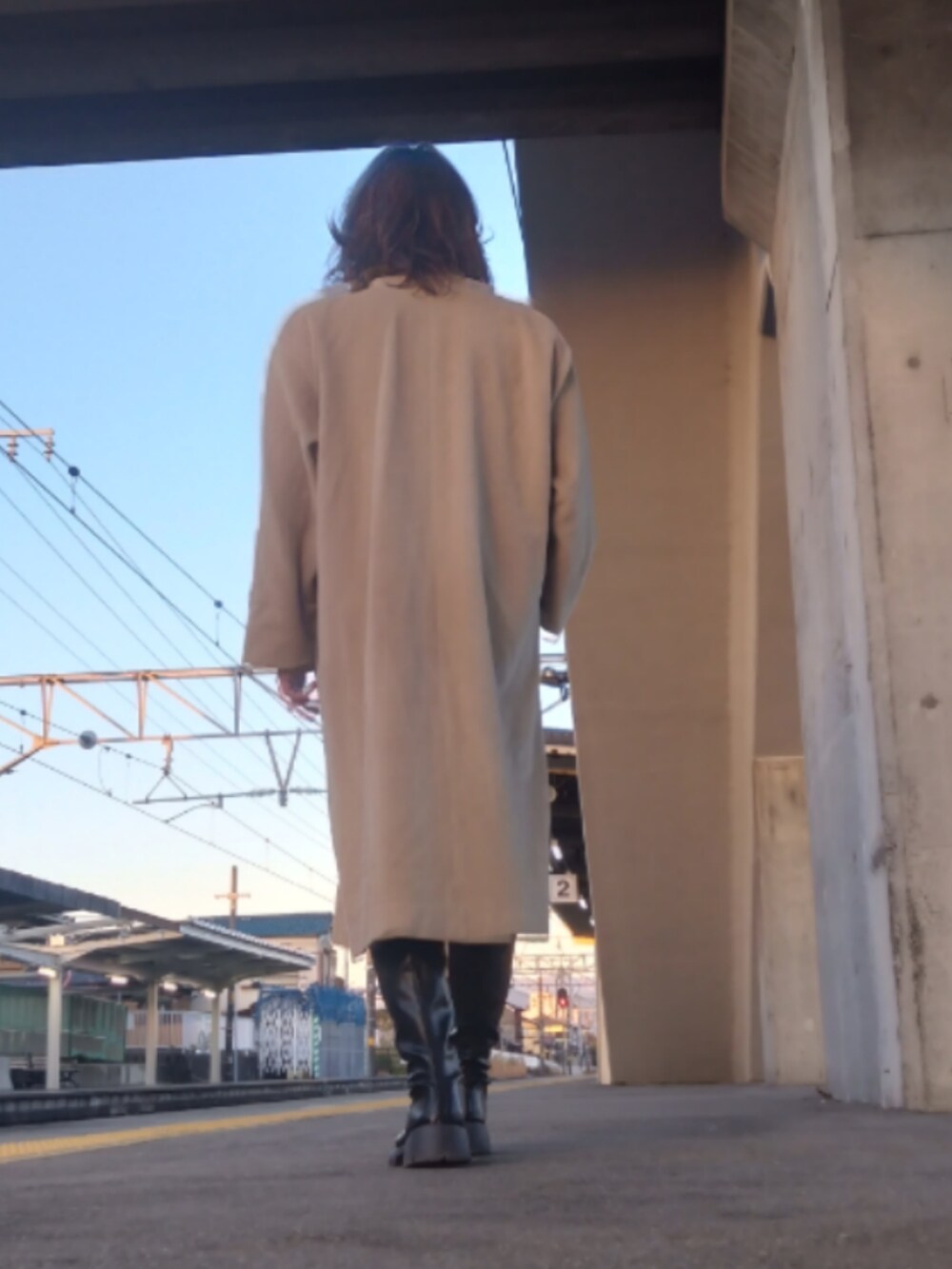 ベージュ系のノーカラーコート、ブラック系のブーツ、ベージュ系のその他パンツを着用したメンズの冬コーディネートの2枚目の写真