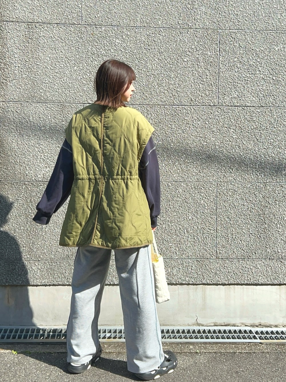 グレー系のスウェットパンツ、ブルー系のスウェット、グリーン系のノーカラージャケットを着用したレディースの春コーディネートの2枚目の写真