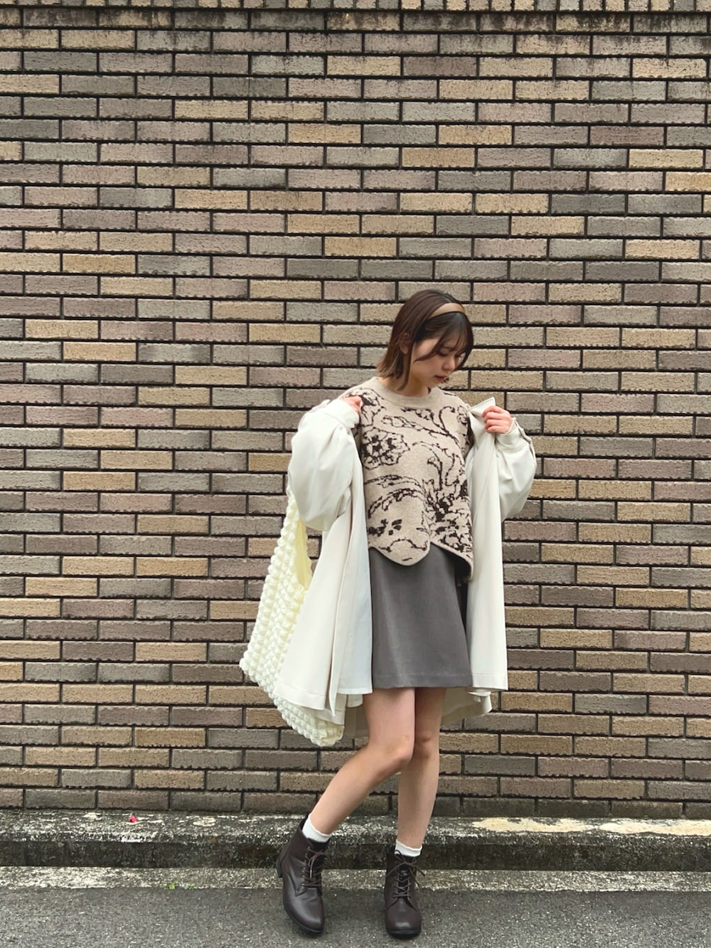 ブラウン系のブーツ、グレー系のスカート、ベージュ系のニット/セーターを着用したレディースの春コーディネートの3枚目の写真