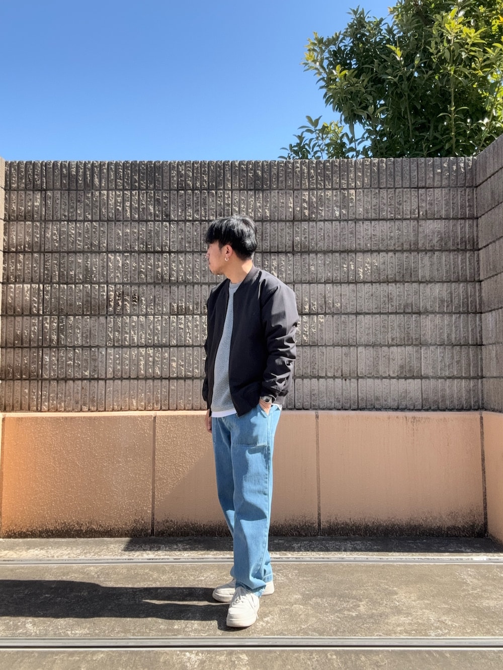 ブラック系のブルゾン、グレー系のTシャツ/カットソー、ブルー系のデニムパンツを着用したメンズの春コーディネートの2枚目の写真