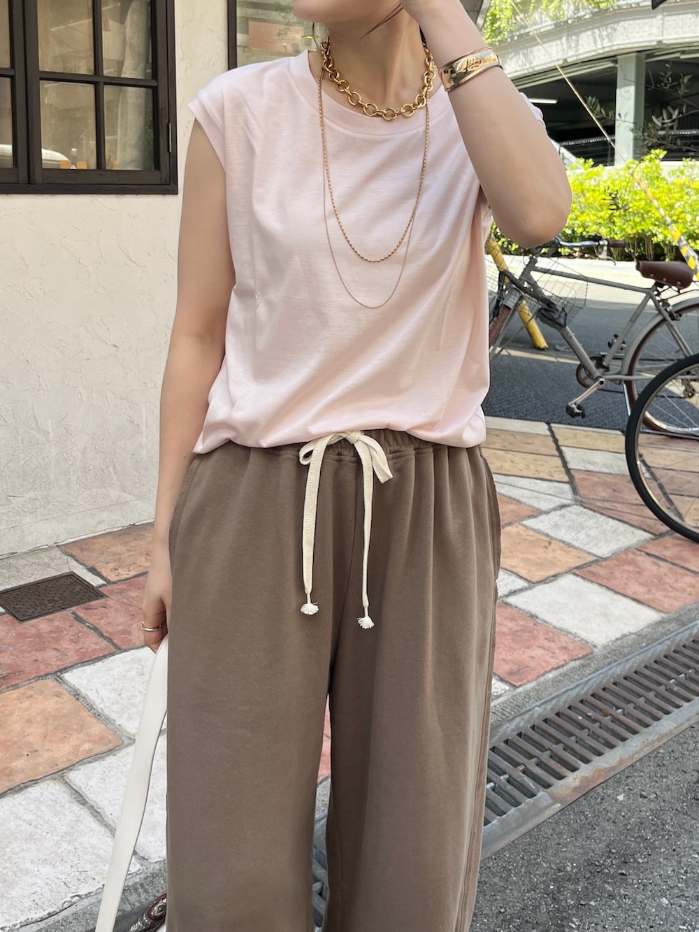 ピンク系のTシャツ/カットソー、ブラウン系のその他パンツ、ホワイト系のショルダーバッグを着用したレディースの春コーディネートの3枚目の写真