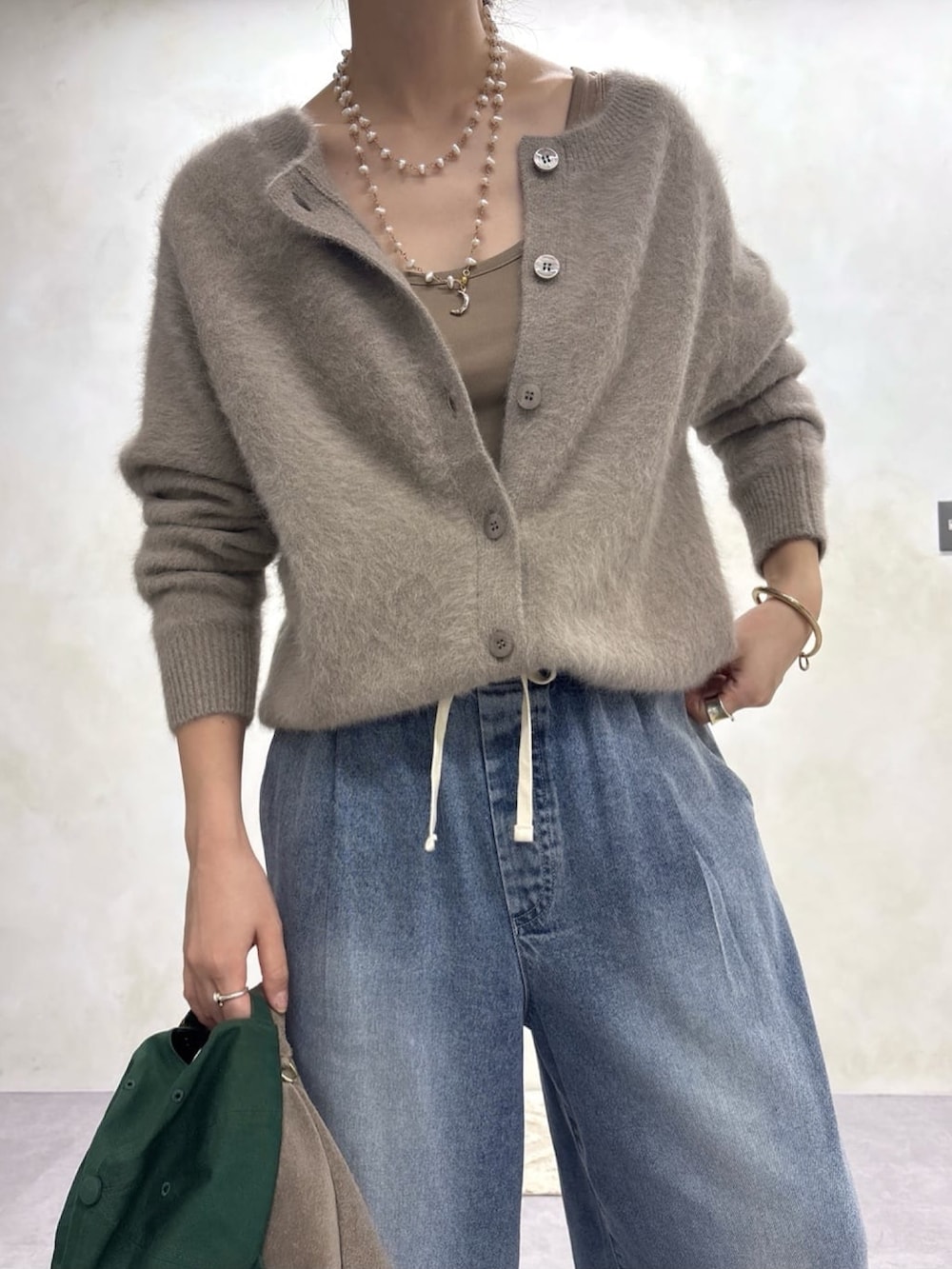 ブラウン系のカーディガン/ボレロ、ブルー系のデニムパンツ、ゴールド系のネックレスを着用したレディースの秋コーディネートの3枚目の写真