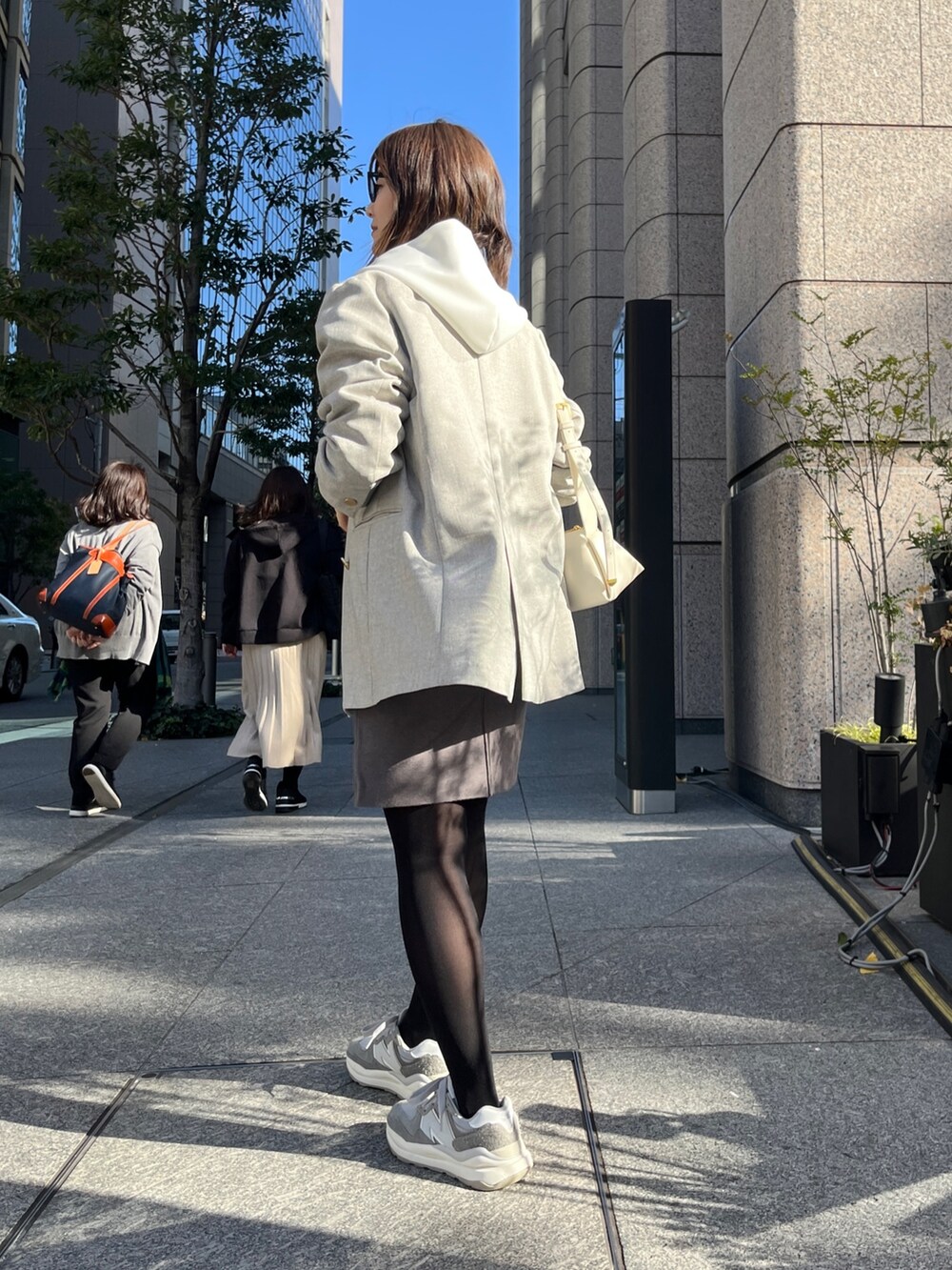 ホワイト系のパーカー、グレー系のテーラードジャケット、グレー系のスカートを着用したレディースの冬コーディネートの9枚目の写真