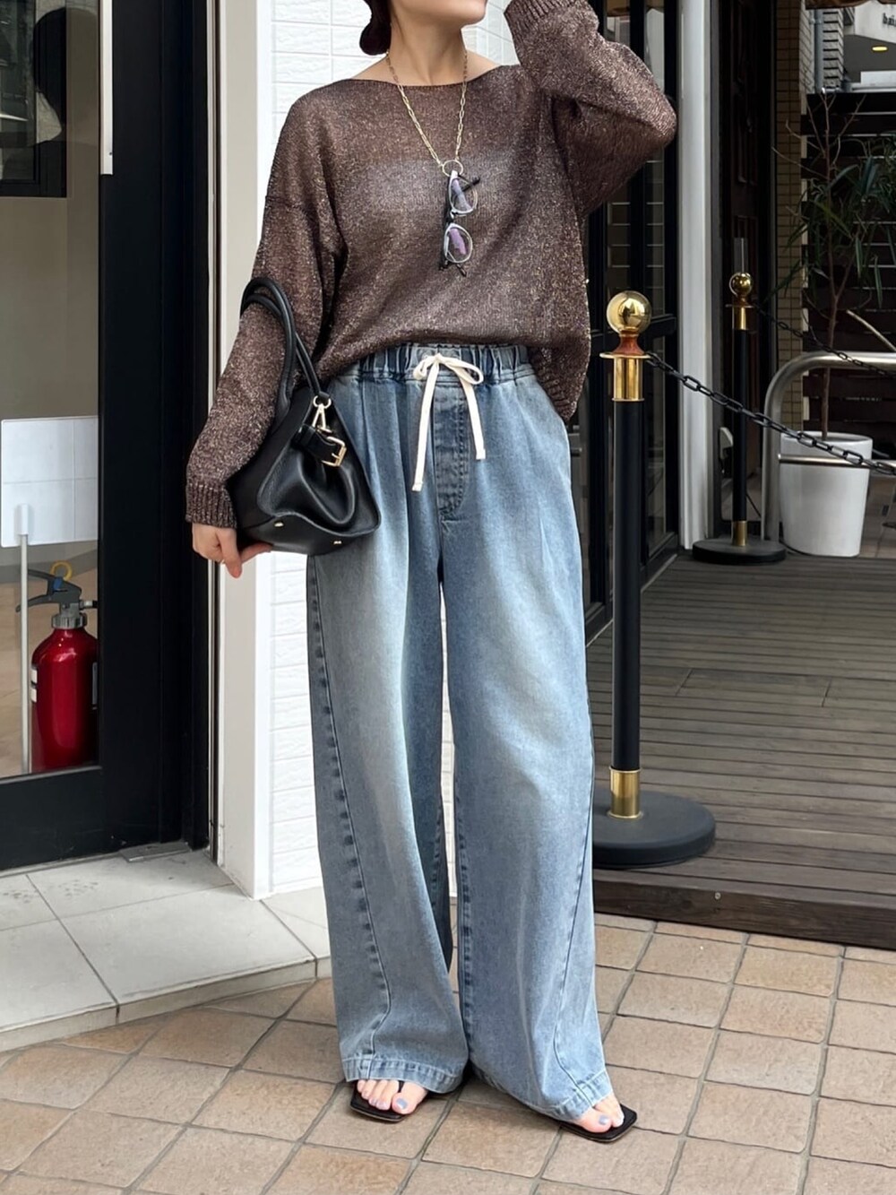 ブラウン系のニット/セーター、ブルー系のデニムパンツ、シルバー系のブーツを着用したレディースの春コーディネートの2枚目の写真