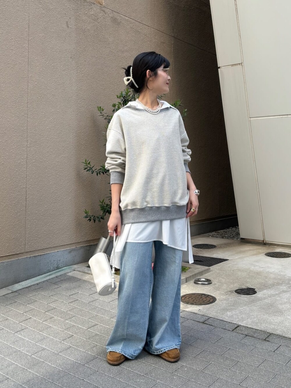 グレー系のTシャツ/カットソー、ホワイト系のシャツ/ブラウス、ブルー系のデニムパンツを着用したレディースの冬コーディネートの4枚目の写真