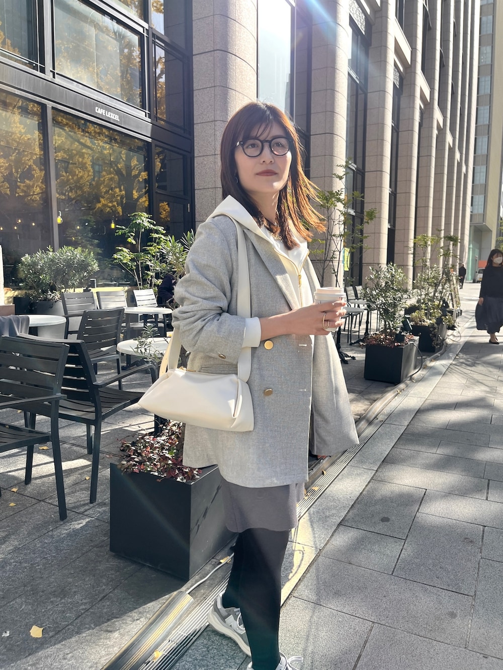 ホワイト系のパーカー、グレー系のテーラードジャケット、グレー系のスカートを着用したレディースの冬コーディネートの8枚目の写真