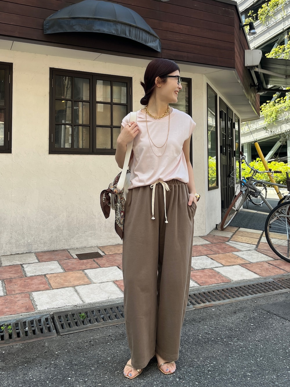 ピンク系のTシャツ/カットソー、ブラウン系のその他パンツ、ホワイト系のショルダーバッグを着用したレディースの春コーディネートの2枚目の写真