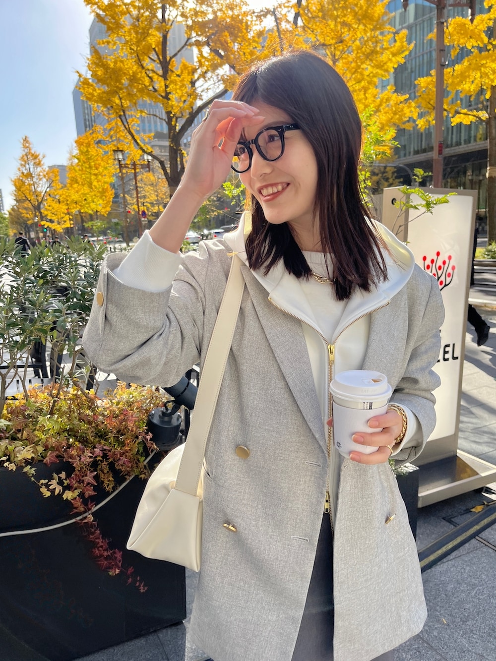 ホワイト系のパーカー、グレー系のテーラードジャケット、グレー系のスカートを着用したレディースの冬コーディネートの6枚目の写真