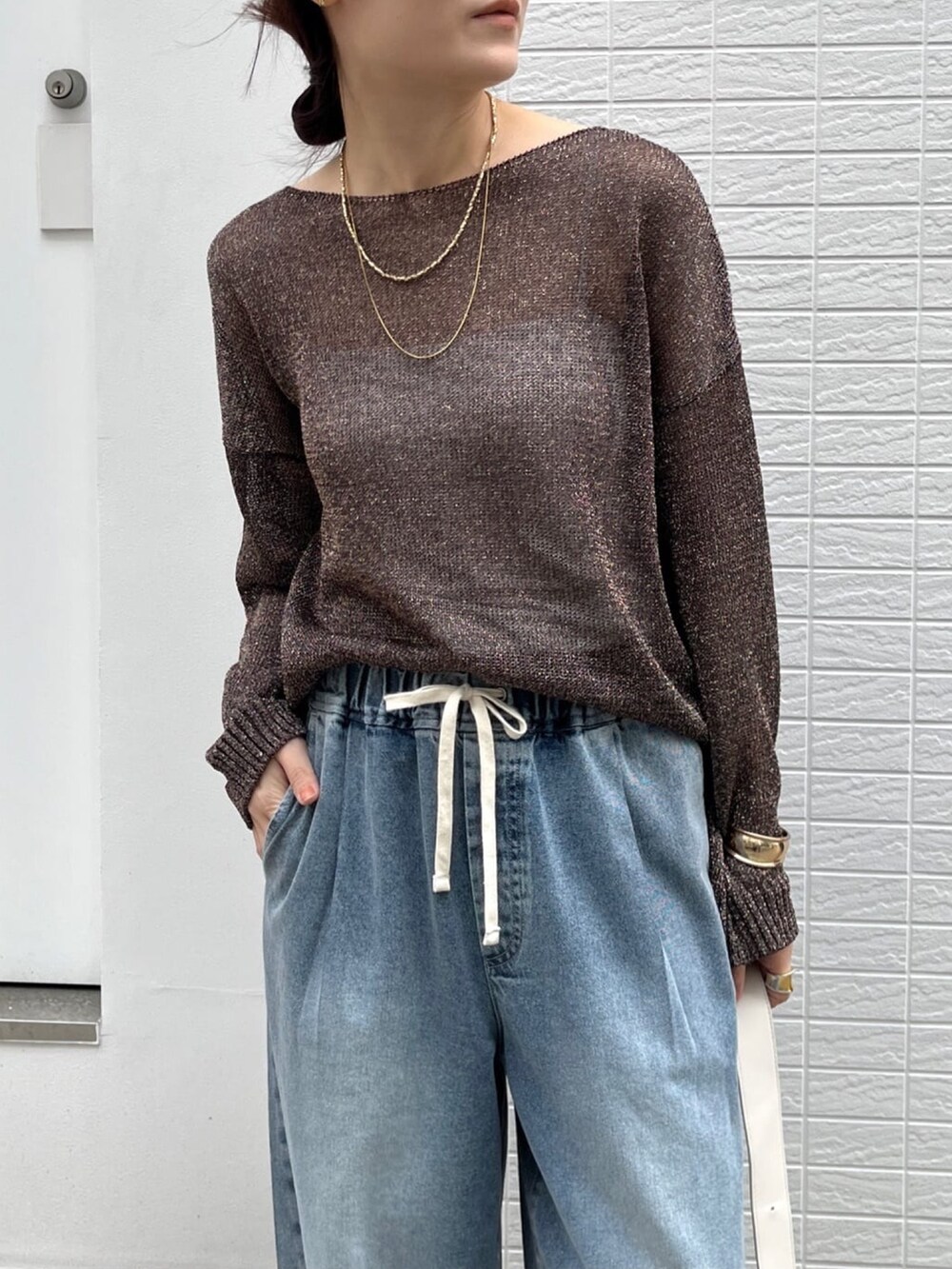 ブラウン系のニット/セーター、ブルー系のデニムパンツ、シルバー系のブーツを着用したレディースの春コーディネートの4枚目の写真