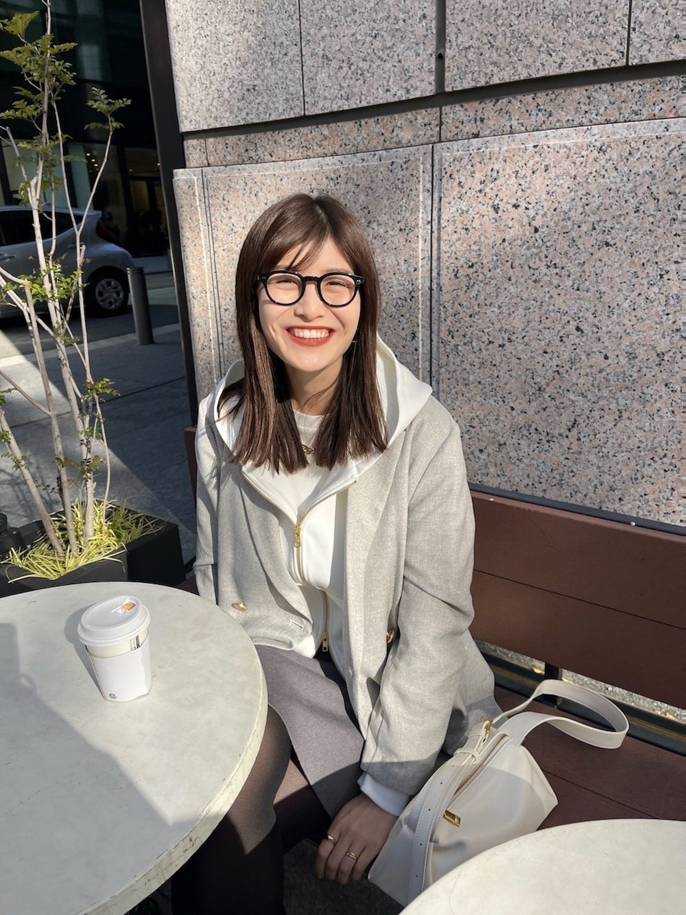 ホワイト系のパーカー、グレー系のテーラードジャケット、グレー系のスカートを着用したレディースの冬コーディネートの3枚目の写真