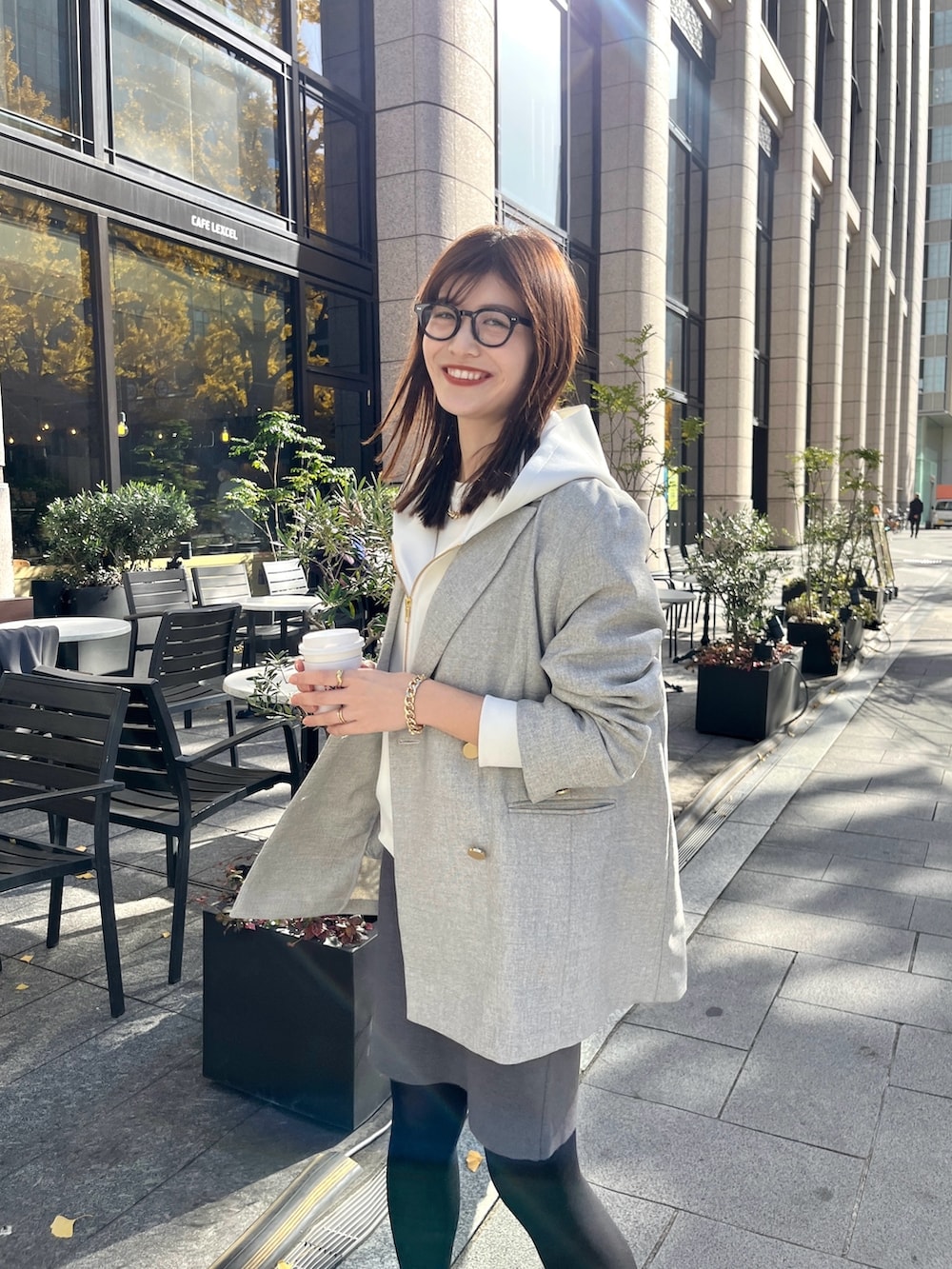 ホワイト系のパーカー、グレー系のテーラードジャケット、グレー系のスカートを着用したレディースの冬コーディネートの2枚目の写真