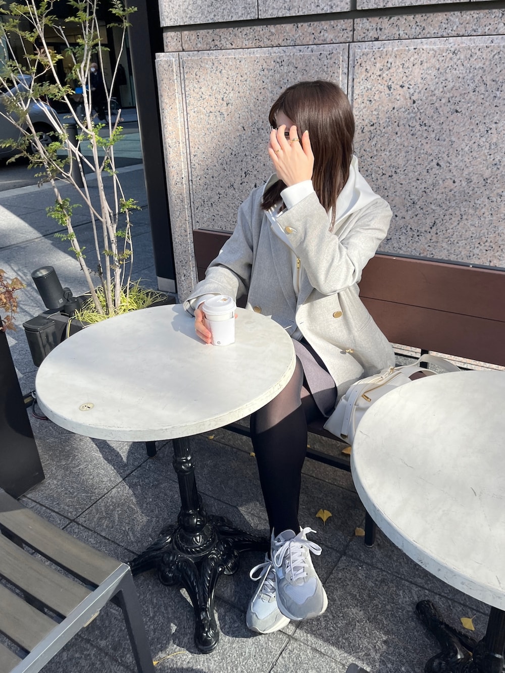 ホワイト系のパーカー、グレー系のテーラードジャケット、グレー系のスカートを着用したレディースの冬コーディネートの4枚目の写真