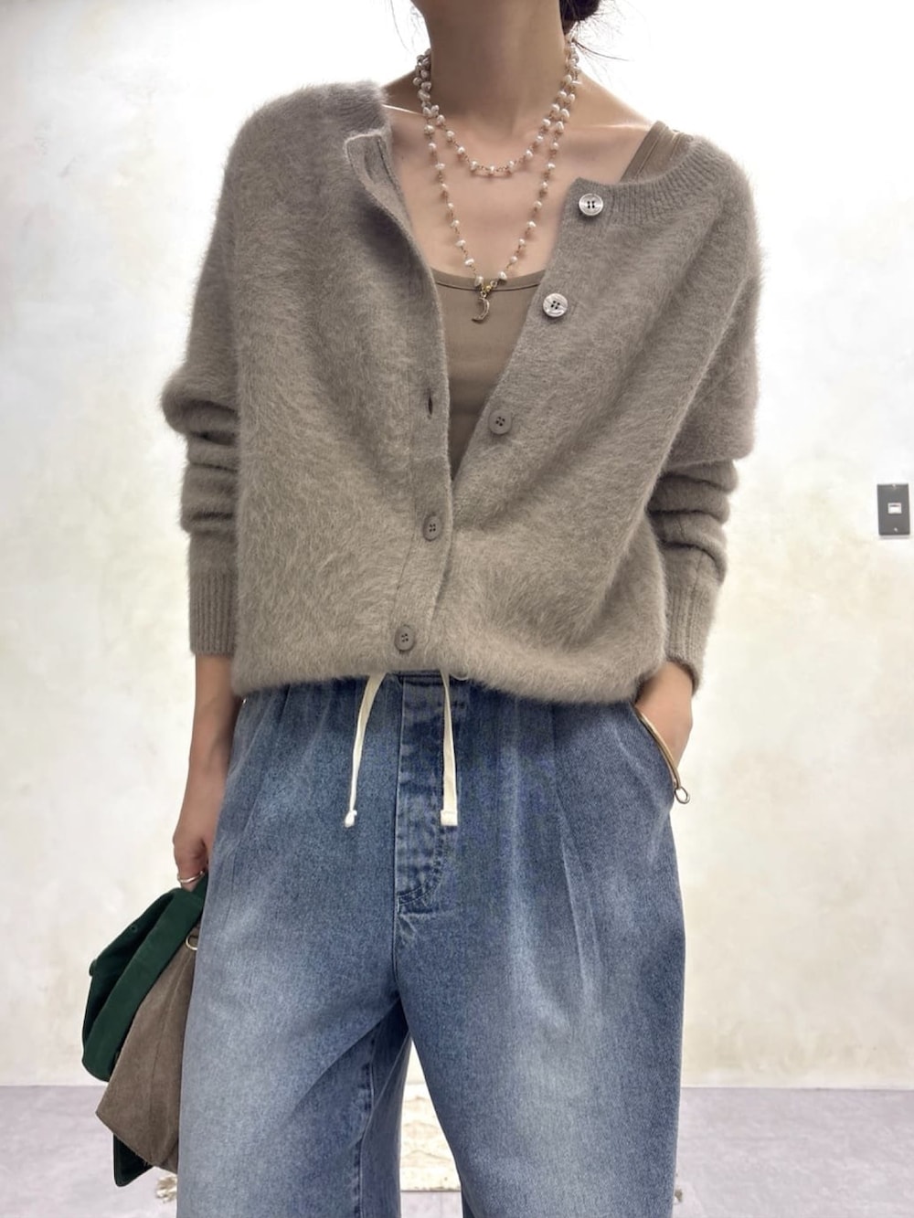 ブラウン系のカーディガン/ボレロ、ブルー系のデニムパンツ、ゴールド系のネックレスを着用したレディースの秋コーディネートの2枚目の写真