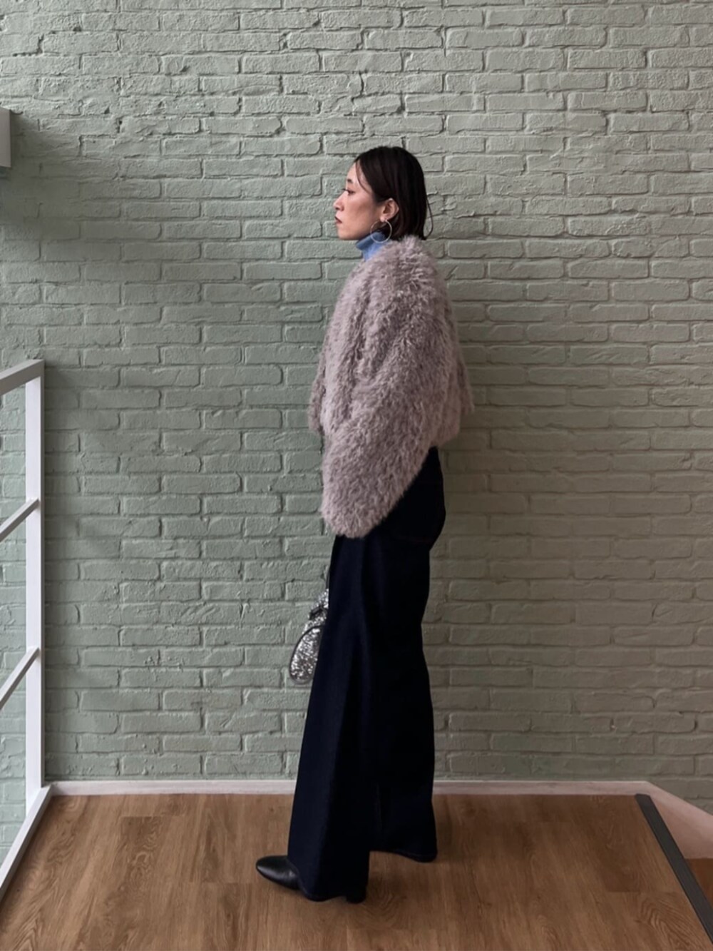 シルバー系のショルダーバッグ、ブルー系のデニムパンツ、グレー系のノーカラージャケットを着用したレディースの秋コーディネートの2枚目の写真