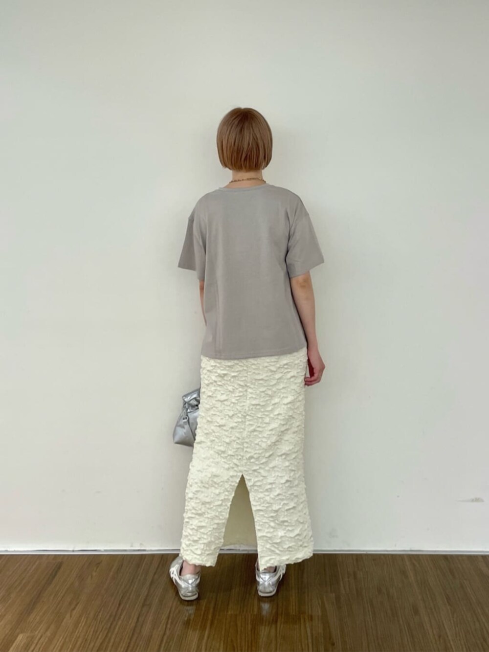 シルバー系のハンドバッグ、ホワイト系のスカート、グレー系のTシャツ/カットソーを着用したレディースの春コーディネートの3枚目の写真