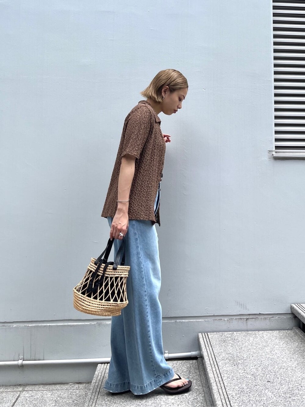 ブラウン系のシャツ/ブラウス、ブルー系のデニムパンツ、ブラック系のハンドバッグを着用したレディースの夏コーディネートの3枚目の写真