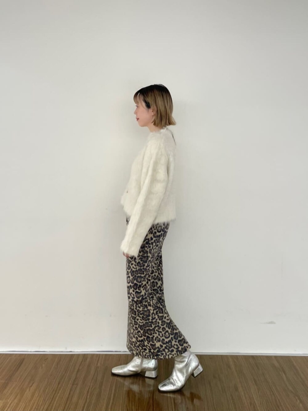 ブラウン系のスカート、ホワイト系のニット/セーター、ゴールド系のネックレスを着用したレディースの秋コーディネートの3枚目の写真