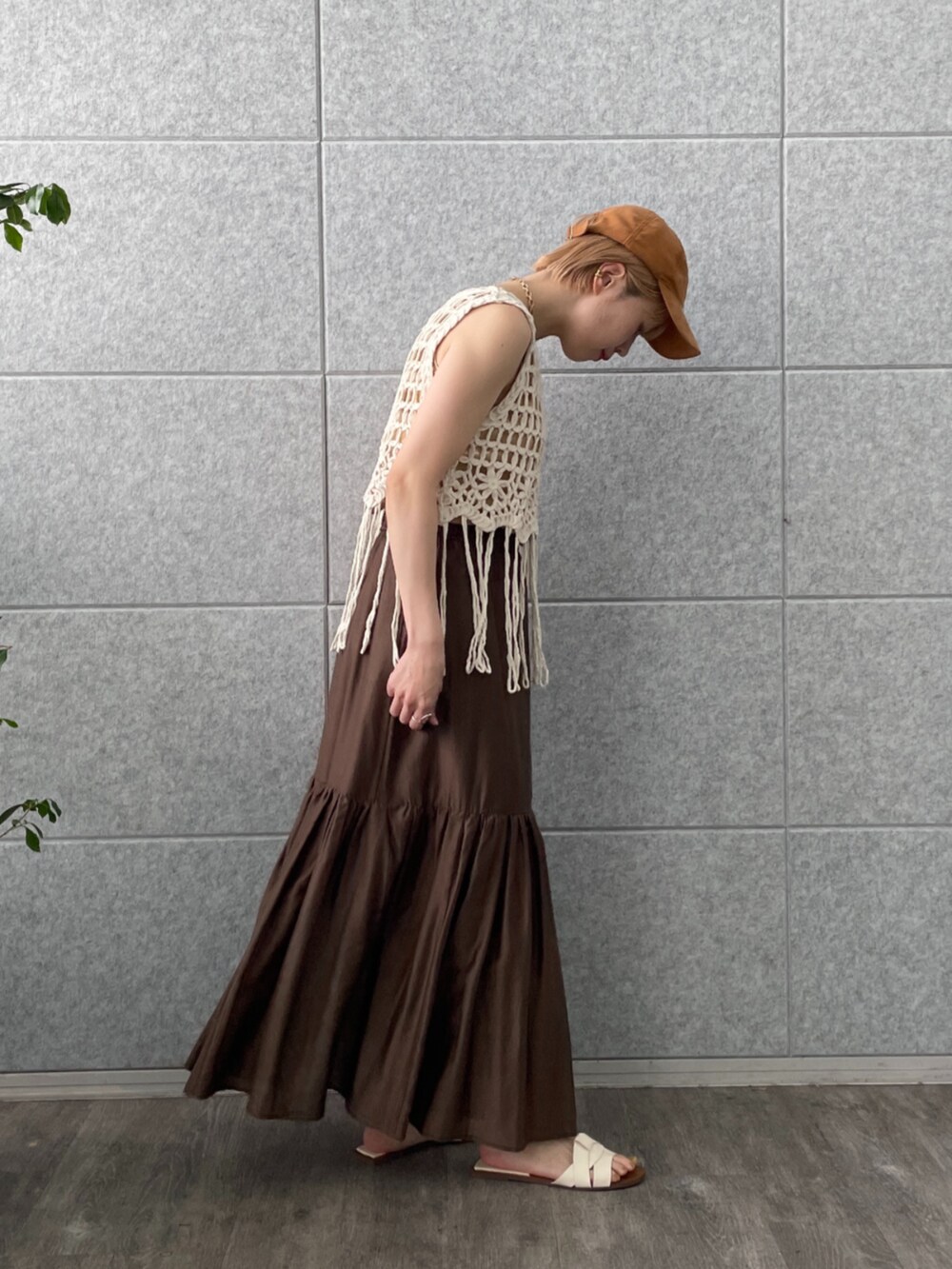 ブラウン系のスカート、ホワイト系のベスト、ゴールド系のタンクトップを着用したレディースの春コーディネートの3枚目の写真