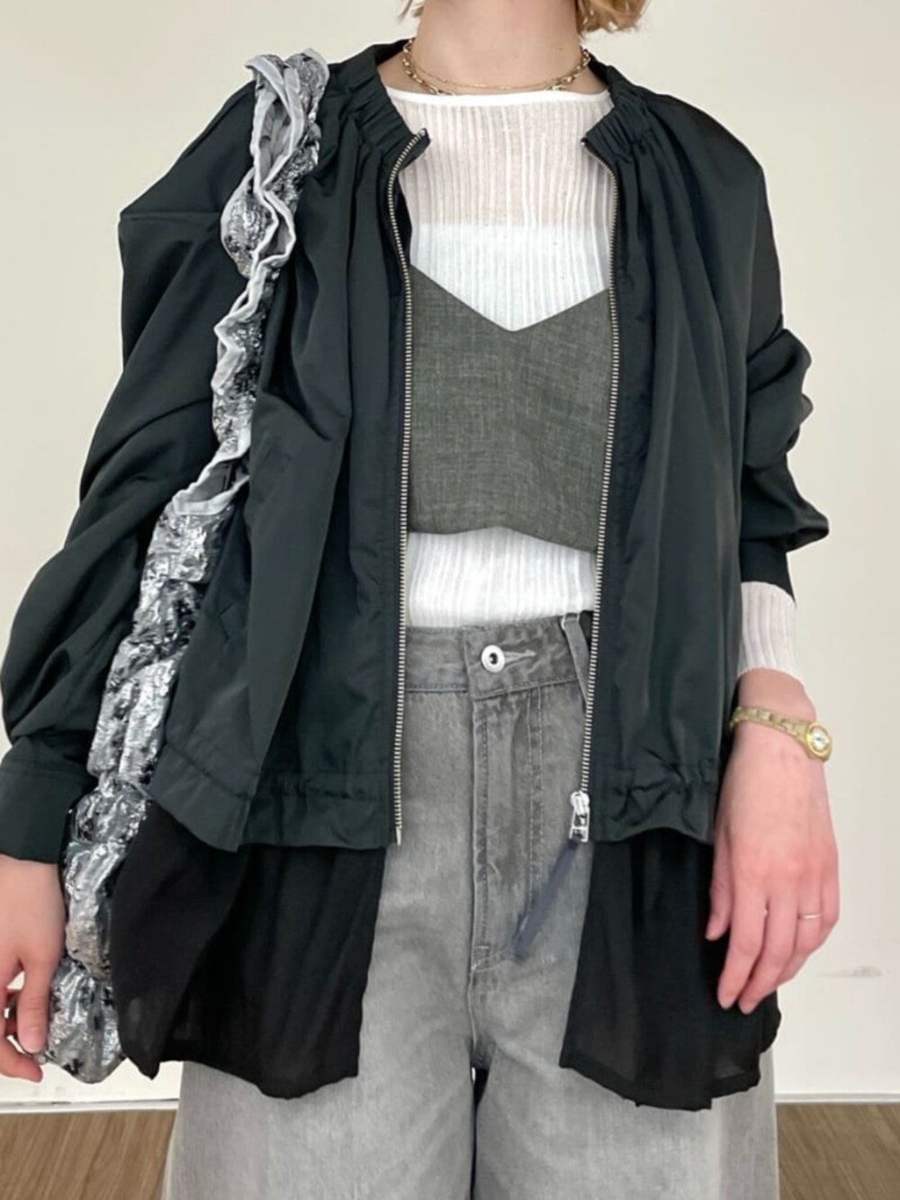 グレー系のデニムパンツ、ホワイト系のニット/セーター、グレー系のブルゾンを着用したレディースの春コーディネートの5枚目の写真