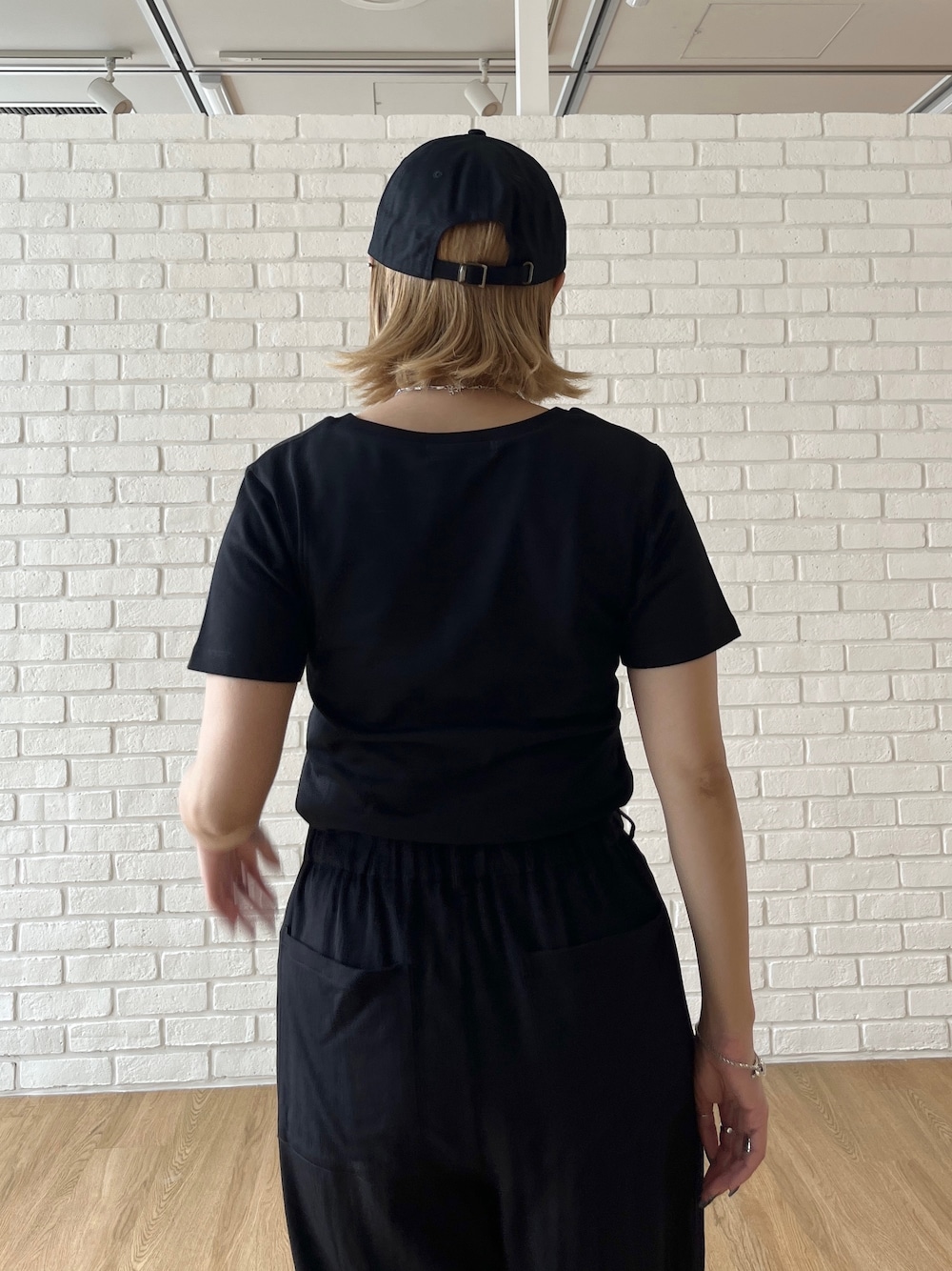 ブラック系のTシャツ/カットソー、ブラック系のその他パンツ、ホワイト系のスニーカーを着用したレディースの夏コーディネートの7枚目の写真