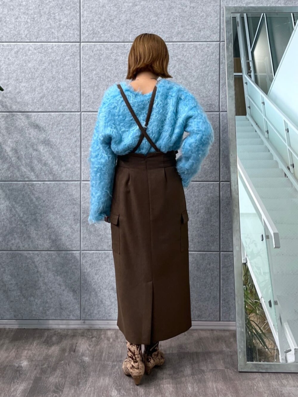 ブラウン系のスカート、ブルー系のニット/セーター、ブラウン系のブーツを着用したレディースの冬コーディネートの2枚目の写真