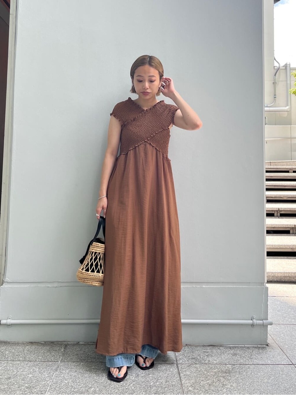 ブラウン系のワンピース、ブルー系のデニムパンツ、ブラック系のハンドバッグを着用したレディースの夏コーディネートの2枚目の写真