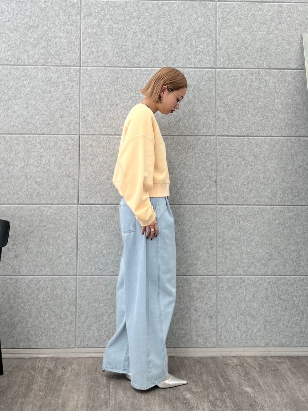 オレンジ系のスウェット、ブルー系のデニムパンツを着用したレディースの春コーディネートの3枚目の写真