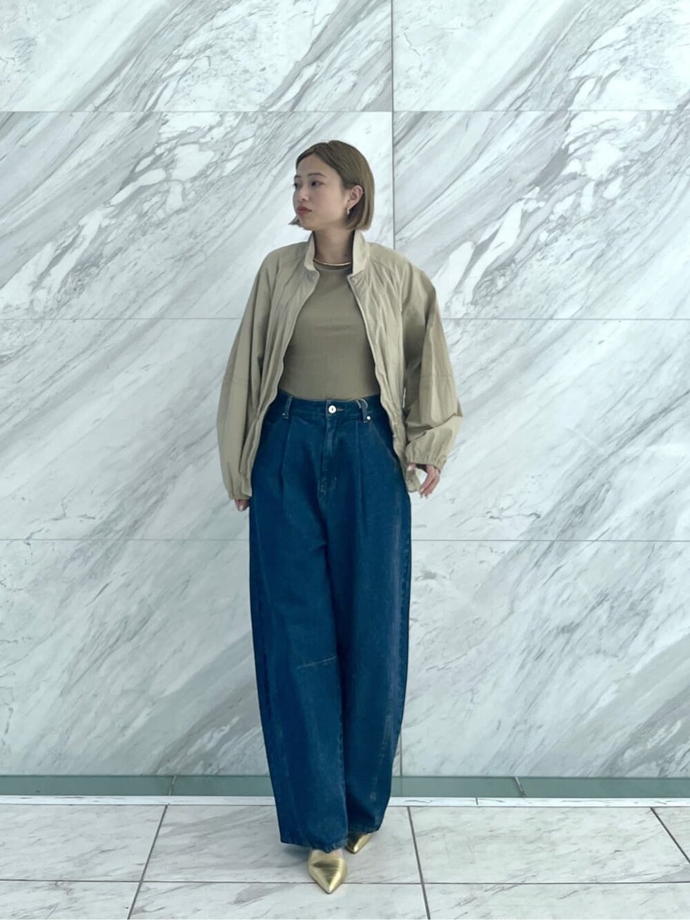 グリーン系のTシャツ/カットソー、ブルー系のデニムパンツ、ベージュ系のブルゾンを着用したレディースの春コーディネートの10枚目の写真