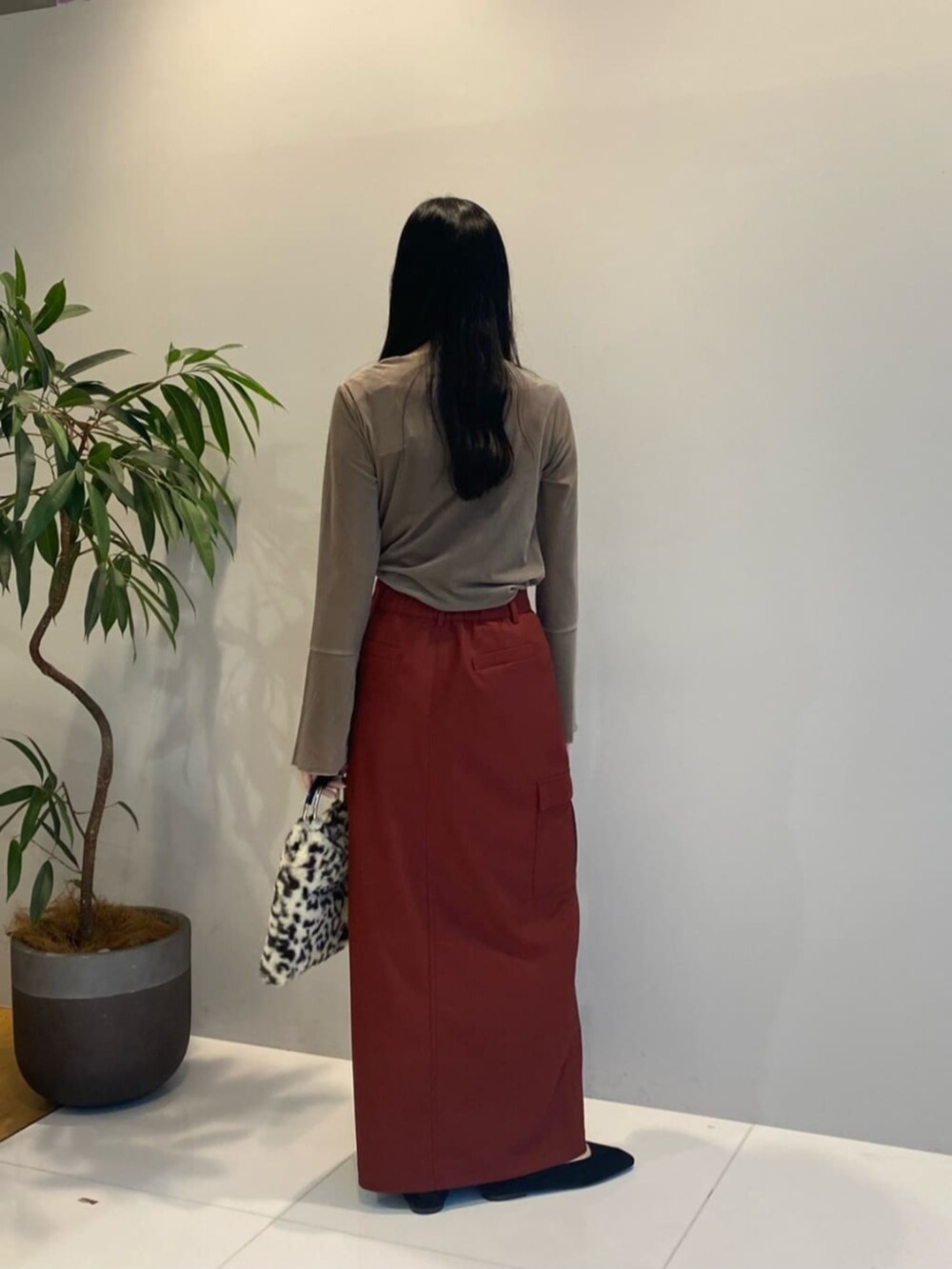 ブラウン系のハンドバッグ、レッド系のスカート、ベージュ系のTシャツ/カットソーを着用したレディースの秋コーディネートの4枚目の写真