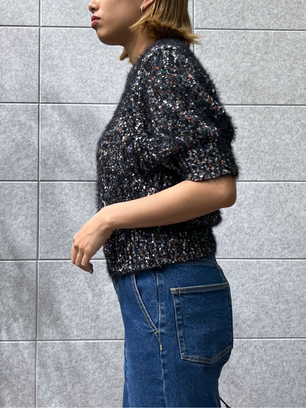 ブラック系のニット/セーター、ブルー系のデニムパンツを着用したレディースの夏コーディネートの8枚目の写真