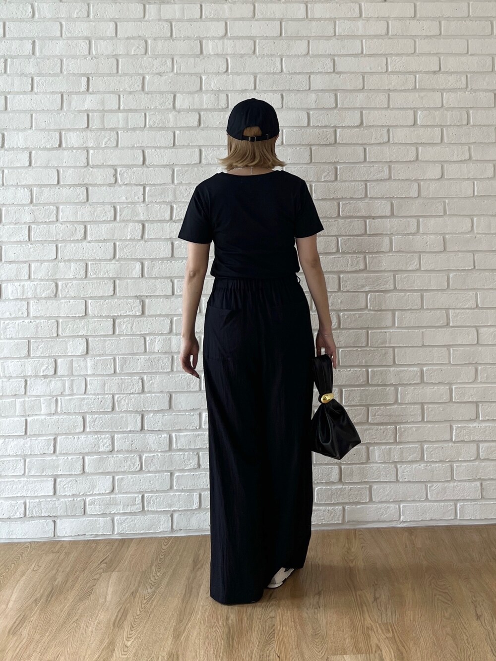 ブラック系のTシャツ/カットソー、ブラック系のその他パンツ、ホワイト系のスニーカーを着用したレディースの夏コーディネートの4枚目の写真