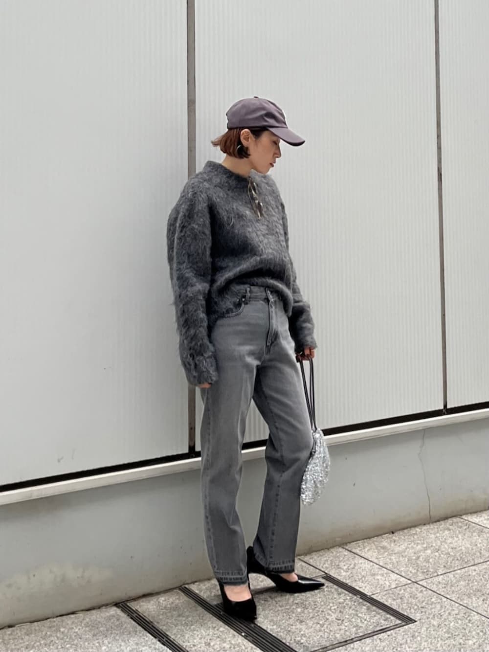 シルバー系のショルダーバッグ、グレー系のデニムパンツ、グレー系のニット/セーターを着用したレディースの秋コーディネートの3枚目の写真