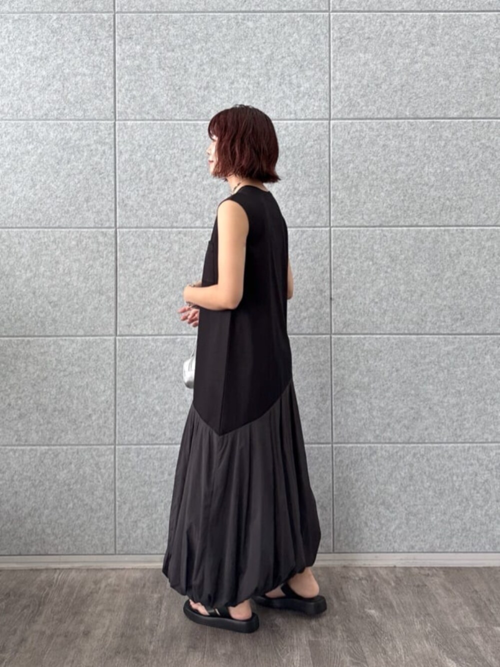 ブラック系のサンダル、シルバー系のハンドバッグ、ブラック系のワンピースを着用したレディースの夏コーディネートの2枚目の写真