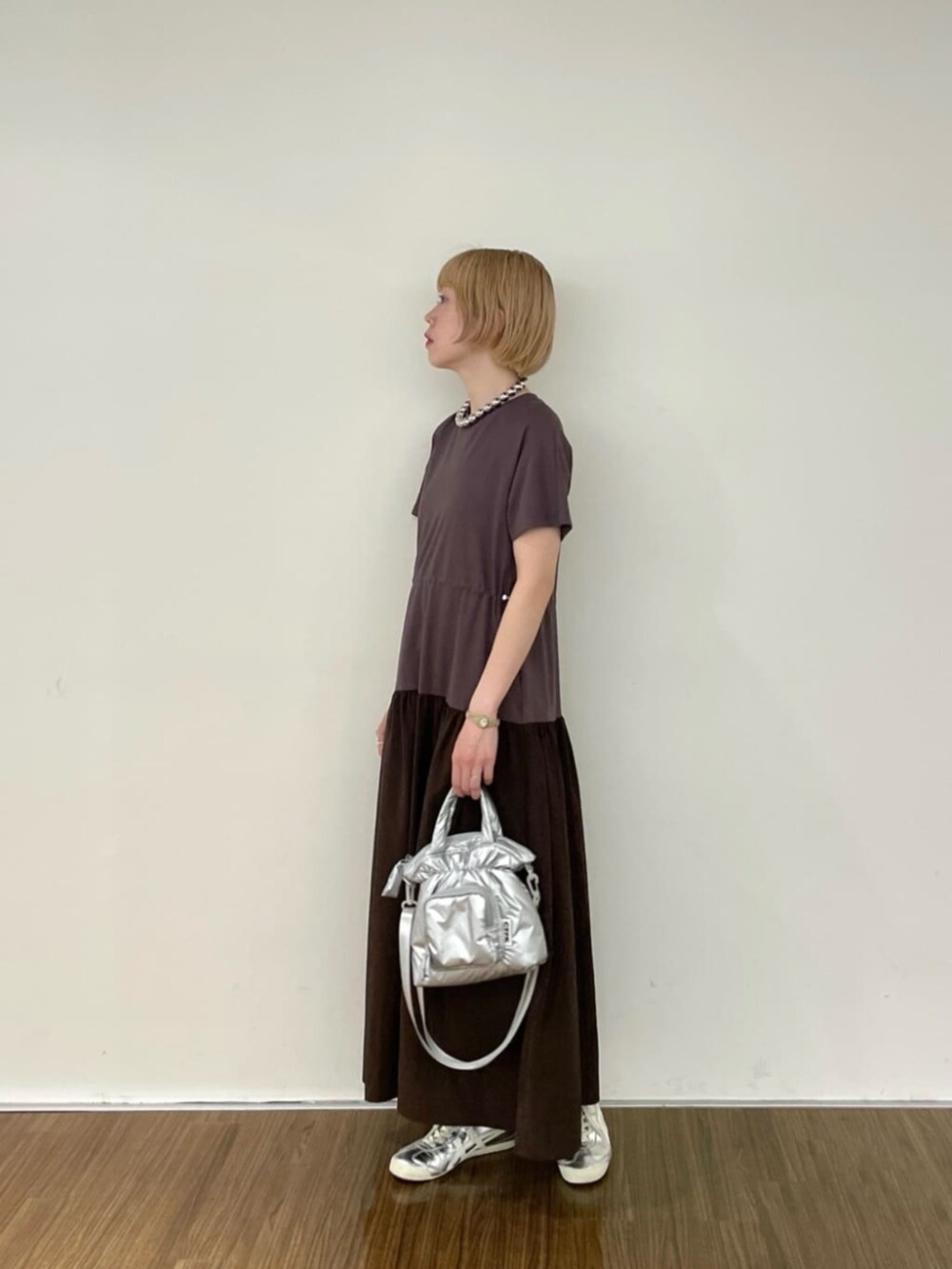シルバー系のハンドバッグ、ブラウン系のワンピースを着用したレディースの春コーディネートの2枚目の写真
