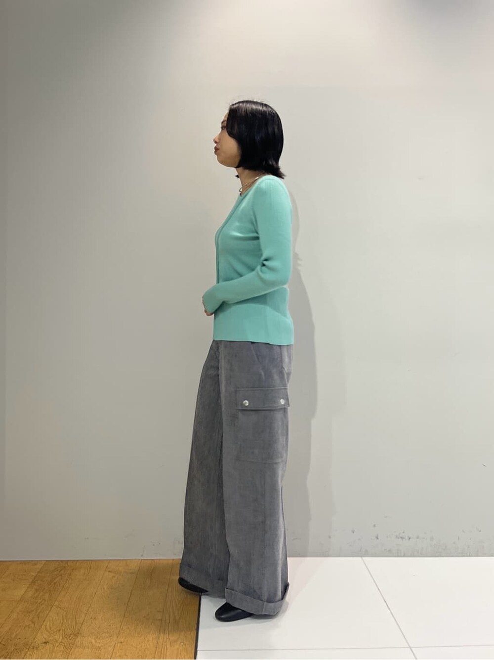 グリーン系のニット/セーター、グレー系のその他パンツ、シルバー系のハンドバッグを着用したレディースの秋コーディネートの2枚目の写真