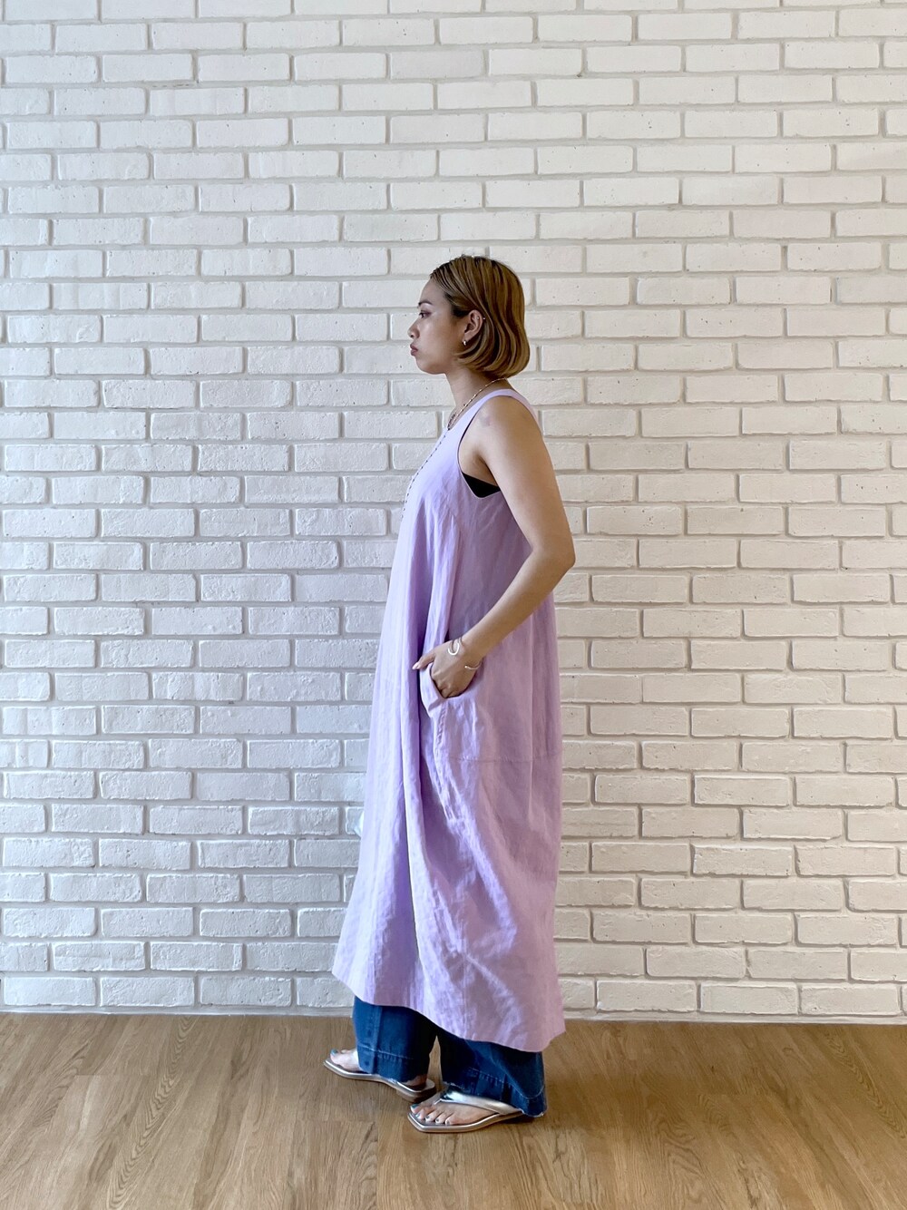 パープル系のワンピース、ブルー系のデニムパンツ、シルバー系のサンダルを着用したレディースの春コーディネートの3枚目の写真