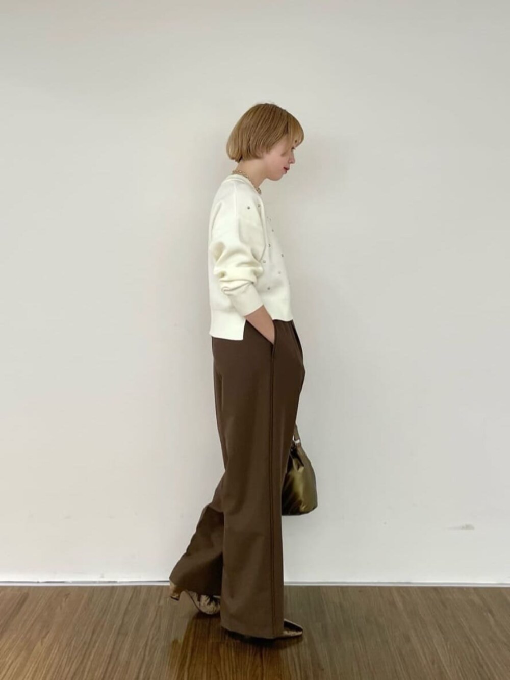 ブラウン系のブーツ、ゴールド系のハンドバッグ、ホワイト系のニット/セーターを着用したレディースの冬コーディネートの2枚目の写真