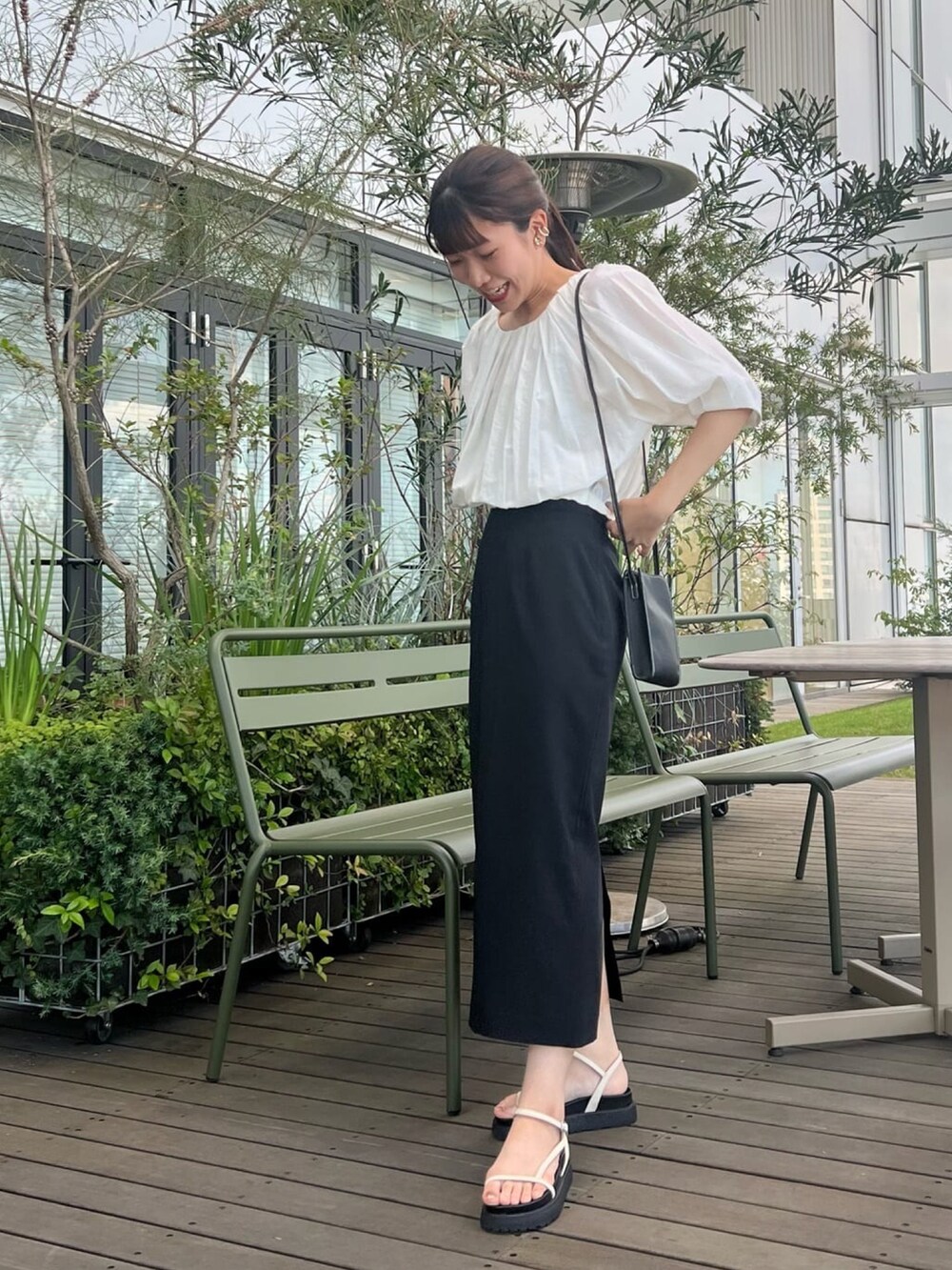 ホワイト系のシャツ/ブラウス、ブラック系のスカート、ブラック系のサンダルを着用したレディースの夏コーディネートの2枚目の写真