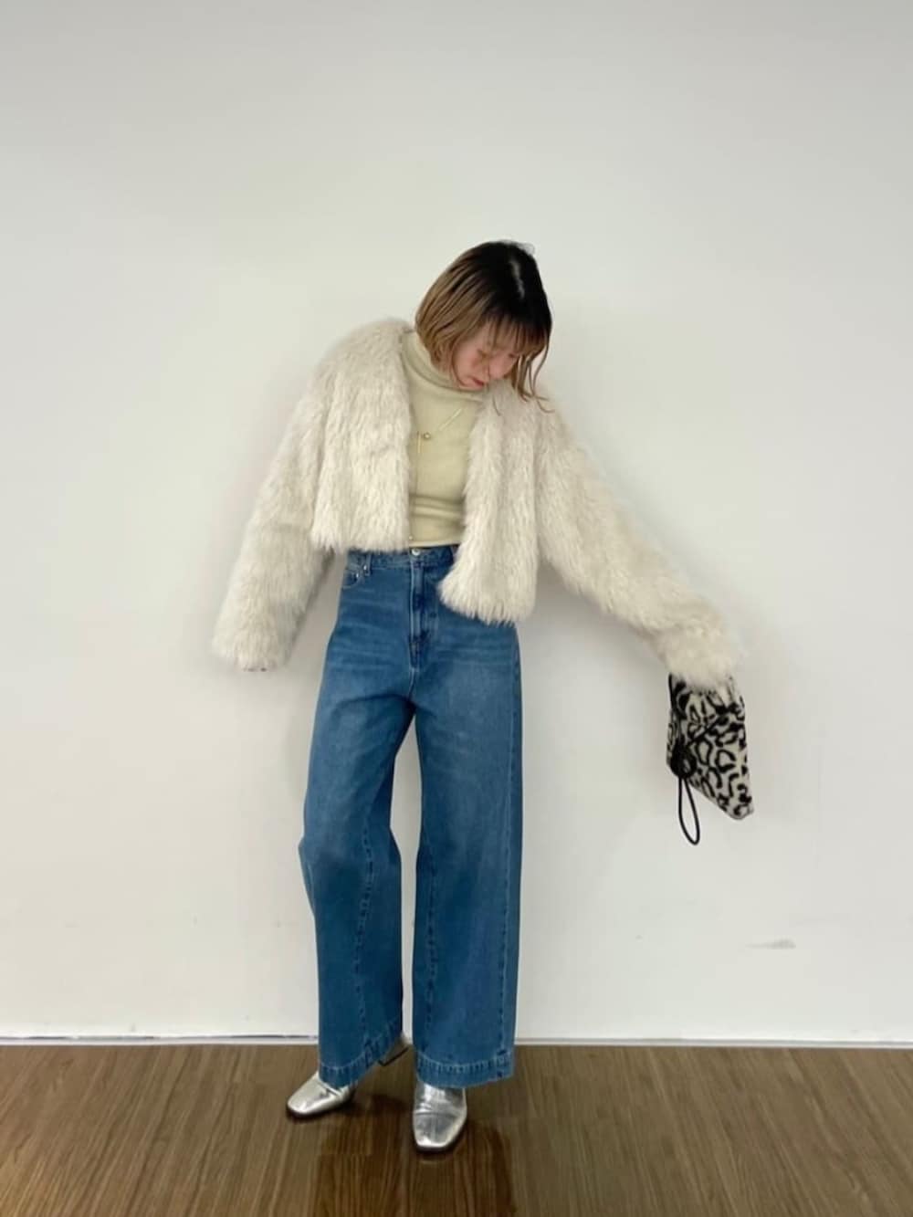 ブラウン系のハンドバッグ、ブルー系のデニムパンツ、ゴールド系のニット/セーターを着用したレディースの秋コーディネートの3枚目の写真