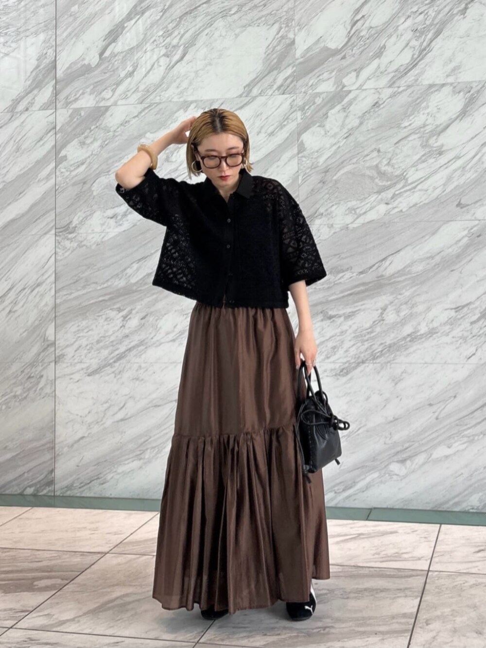 ブラウン系のスカート、ブラック系のシャツ/ブラウスを着用したレディースの春コーディネートの3枚目の写真