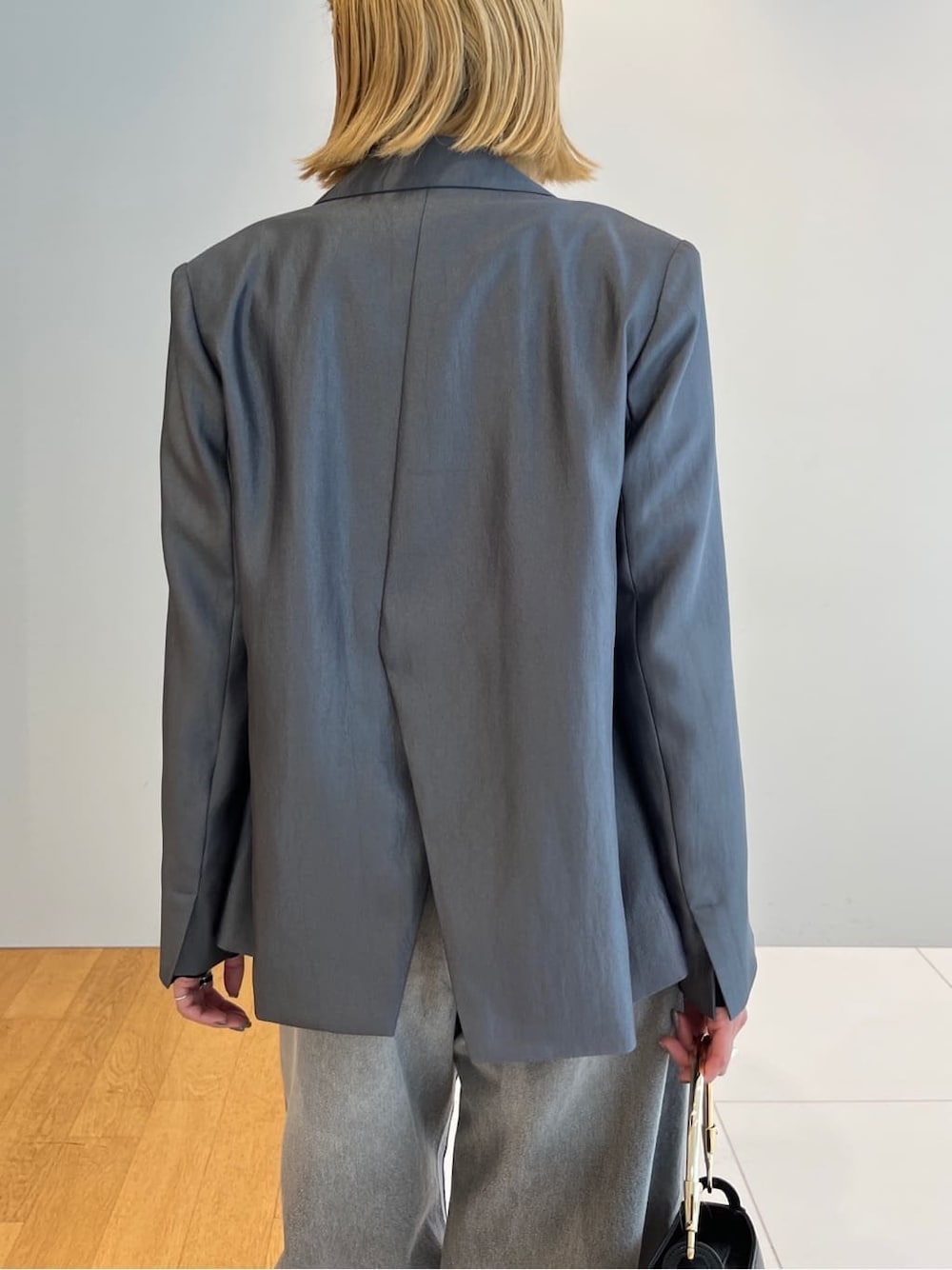 グレー系のテーラードジャケット、ブラック系のニット/セーター、グレー系のデニムパンツを着用したレディースの春コーディネートの7枚目の写真