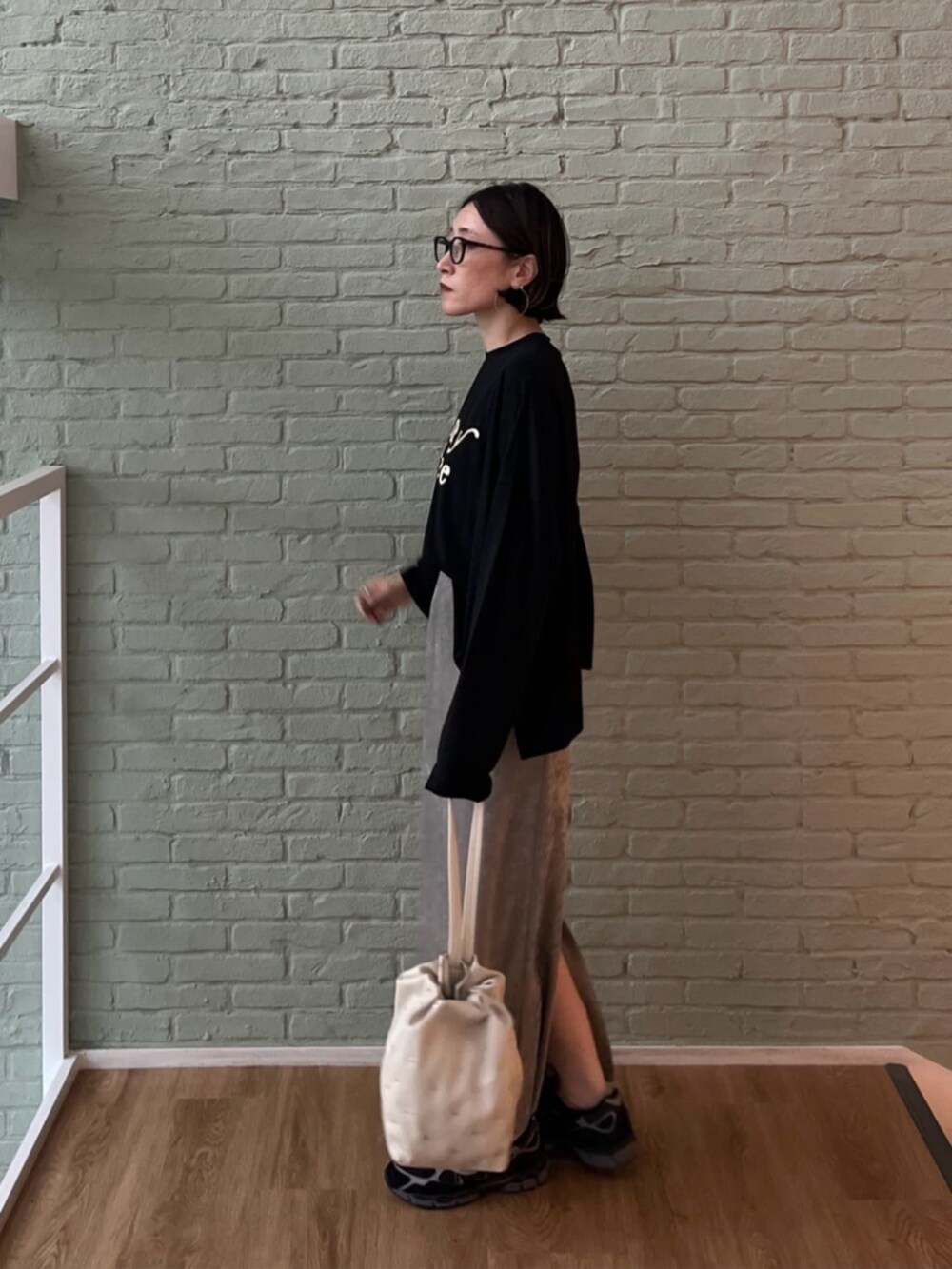 シルバー系のスカート、ブラック系のTシャツ/カットソー、ホワイト系のハンドバッグを着用したレディースの秋コーディネートの4枚目の写真