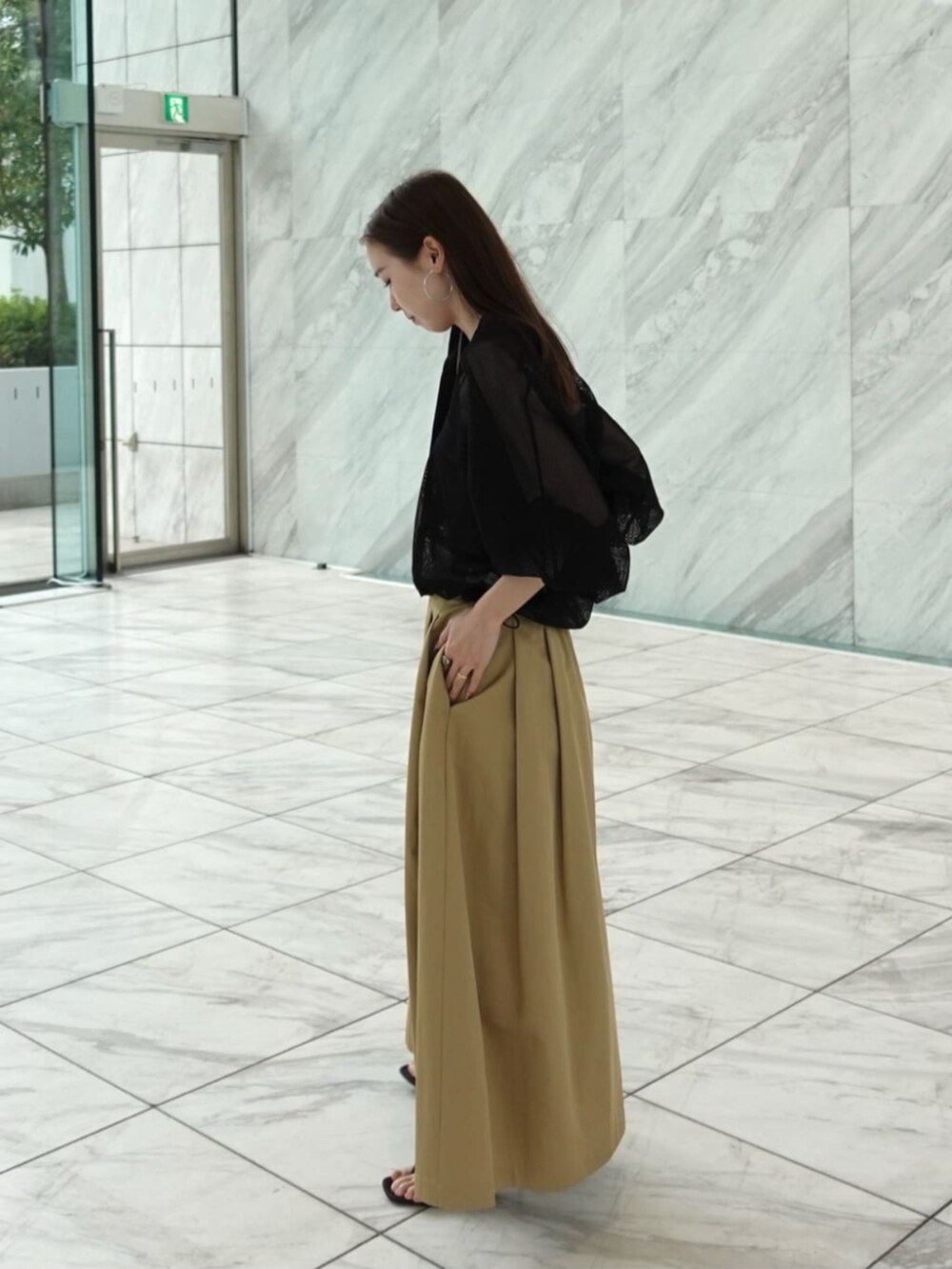 ベージュ系のスカート、ブラック系のブルゾンを着用したレディースの春コーディネートの2枚目の写真