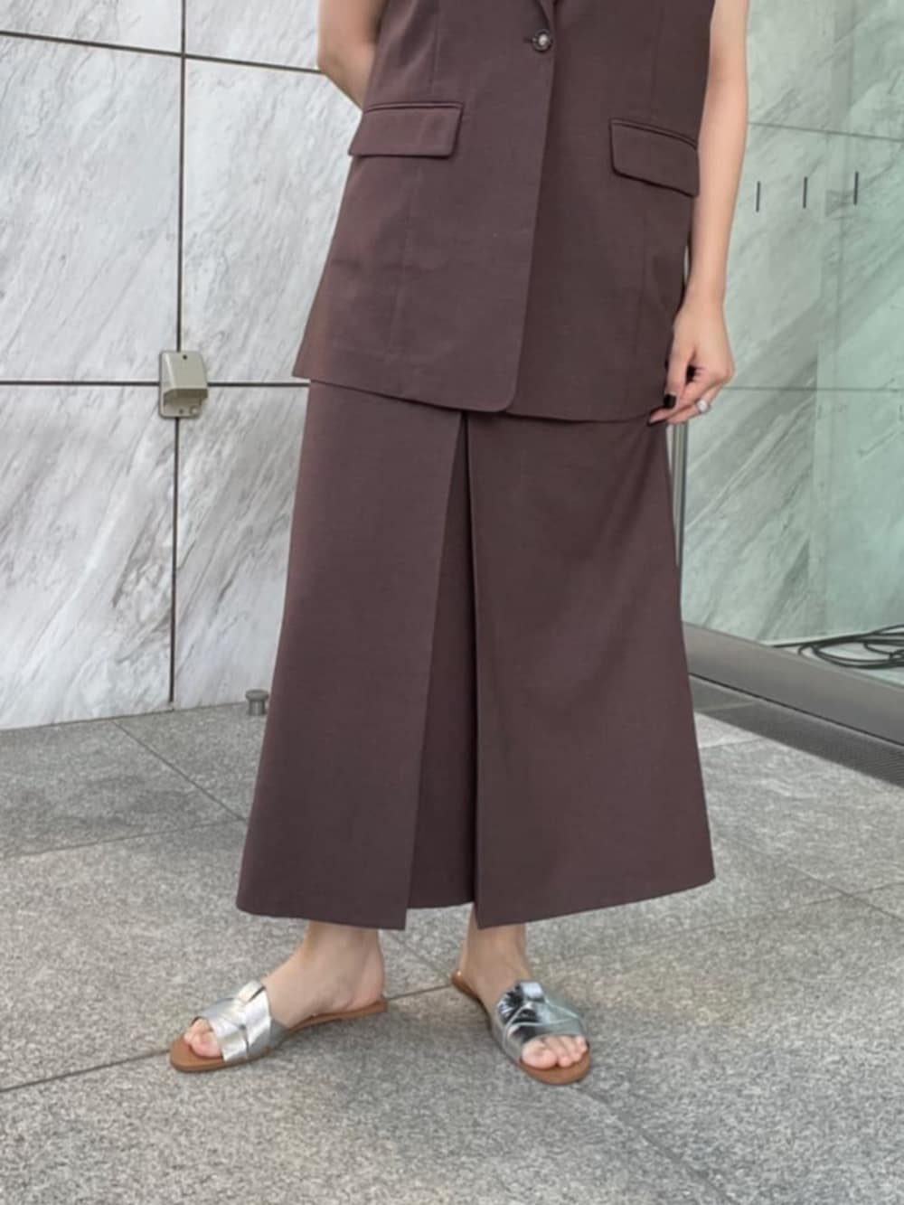 シルバー系のタンクトップ、ブラウン系のベスト、ブラウン系のスカートを着用したレディースの夏コーディネートの5枚目の写真