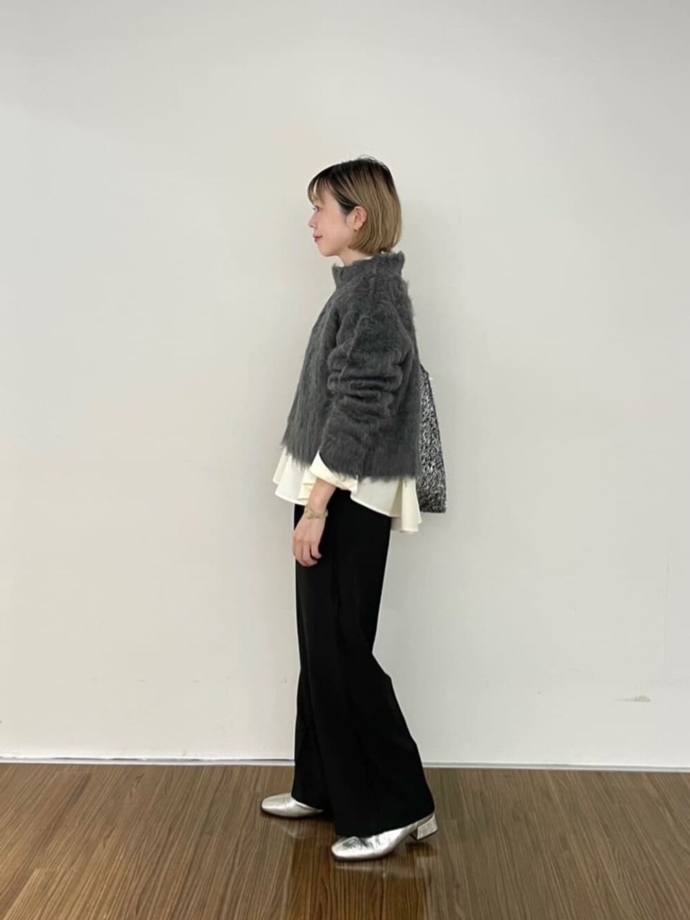 グレー系のニット/セーター、ホワイト系のシャツ/ブラウス、ブラック系のその他パンツを着用したレディースの秋コーディネートの2枚目の写真