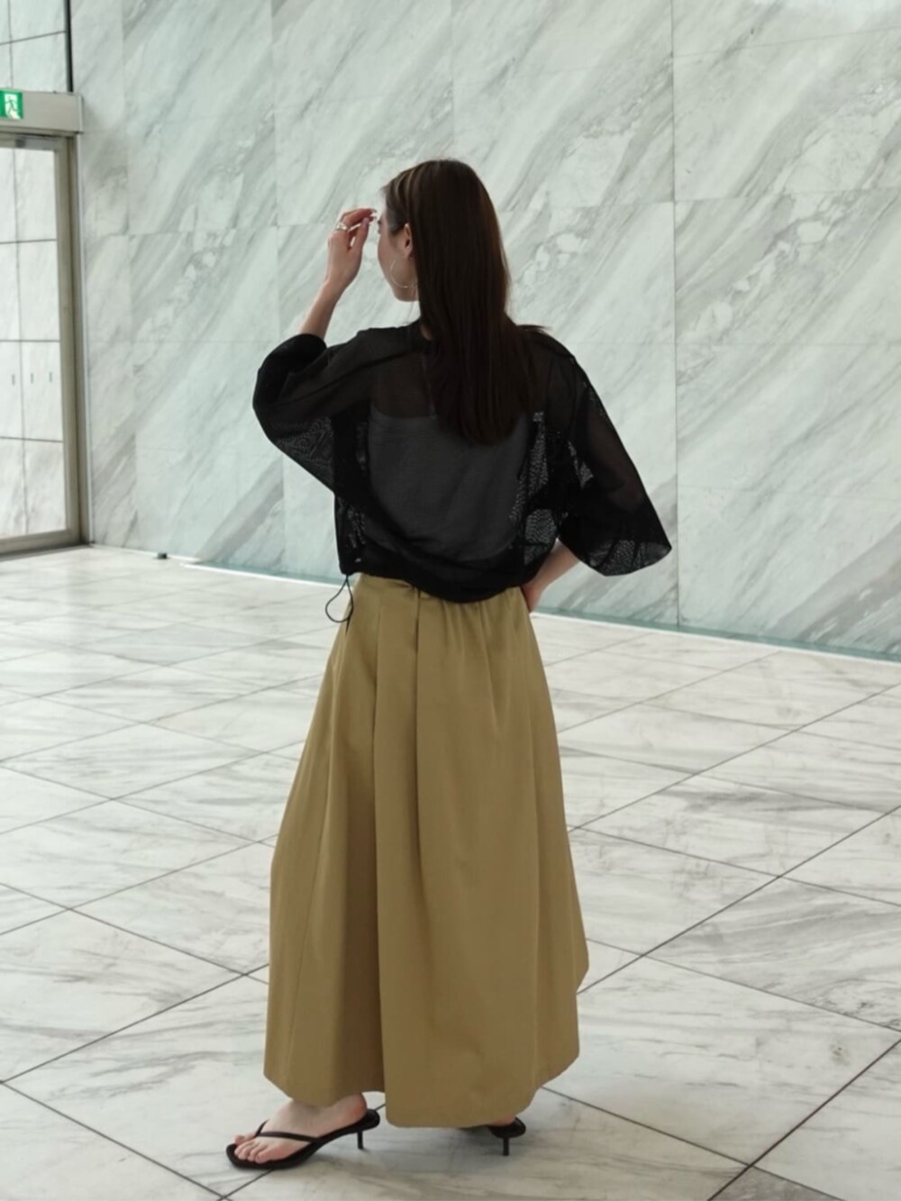 ベージュ系のスカート、ブラック系のブルゾンを着用したレディースの春コーディネートの3枚目の写真