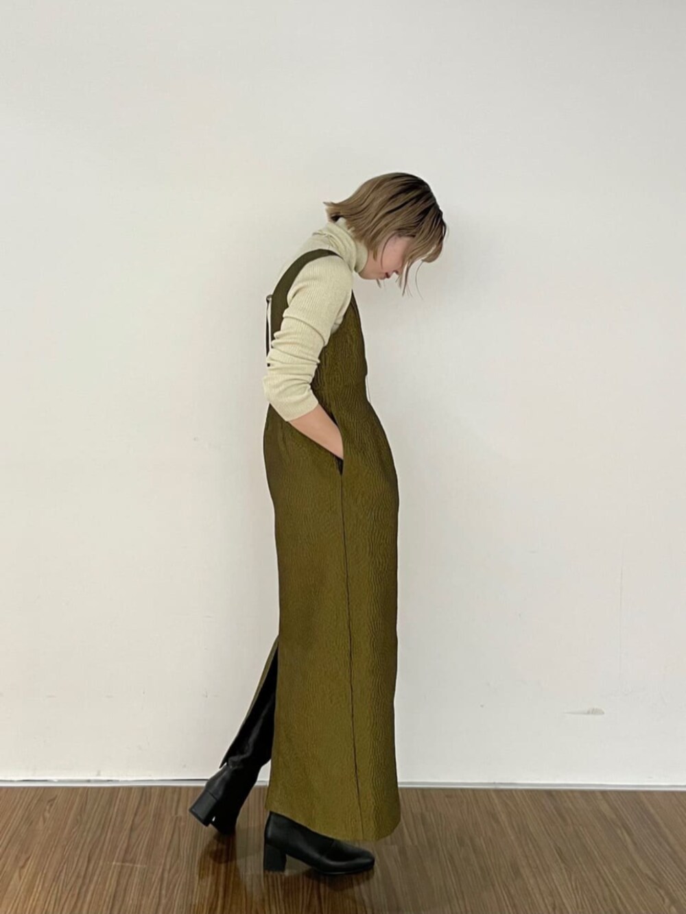 ブラック系のブーツ、グリーン系のワンピース、ゴールド系のニット/セーターを着用したレディースの秋コーディネートの3枚目の写真